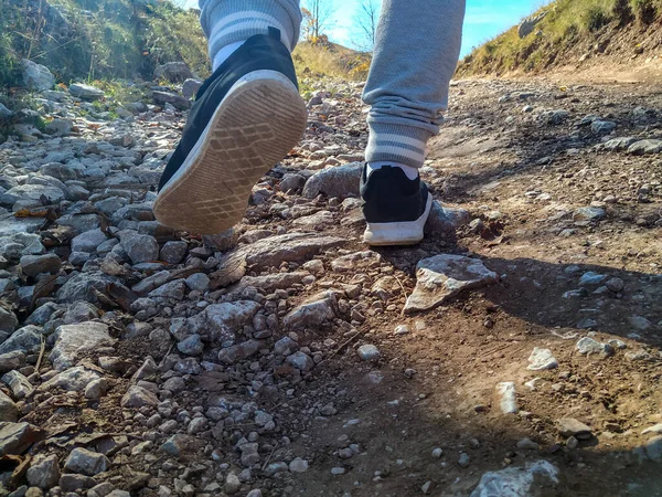 Close-up de calçados esportivos masculinos e pernas enquanto corre na natureza em um terreno difícil rochoso. Procurando uma viagem em um ambiente natural — Fotografia de Stock