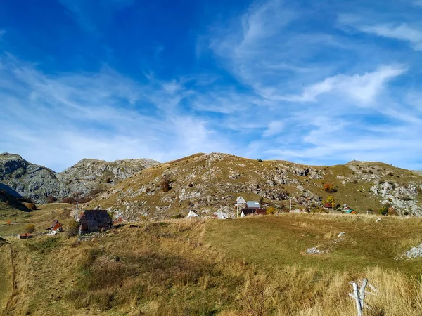 Pequeño pueblo aislado en las montañas para vivir idílico en la naturaleza con vistas a las cadenas montañosas y tejados de casas rodeadas de hierba verde — Foto de Stock