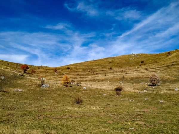 Campo de hierba verde y colinas en un hermoso día majestuoso y tranquilo durante la temporada de otoño a pie en el paisaje de montaña como fondo de pantalla —  Fotos de Stock