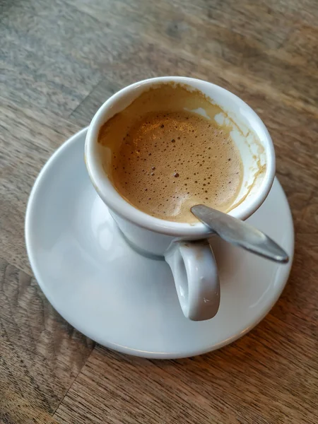 Beyaz bardakta latte ve ahşap masada taze ve sıcak bir içecekle servis edilen Espresso.