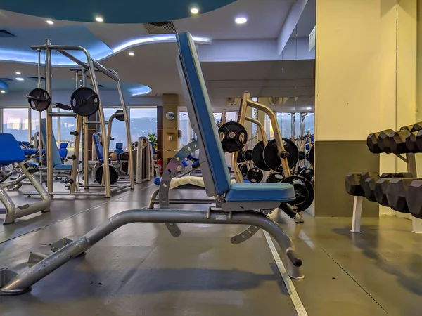 İç mekanda ağırlık kaldırmak ve vücut geliştirmek için yedek kulübesinde modern boş bir spor salonunda sağlıklı yaşam tarzı ve eğlence için bir sürü ekipman var.
