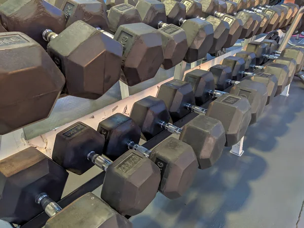 Professional black gym dumbbells stacked next to each other for every day exercise and strength training, power lifting and increasing muscles