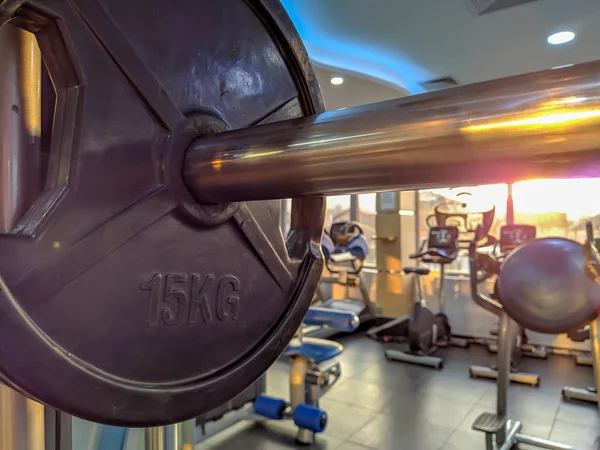 Sun shining on 15 kilogram metal weight for bodybuilding and weight lifting with professional gym equipment around — Stock Photo, Image