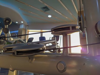 Spor salonunda güneş parıldıyor. Günlük antrenman sırasında ağırlık kaldırmak, profesyonel ve eğlence amaçlı vücut geliştirme için yedek kulübesinde modern ekipmanlar eğitiliyor.