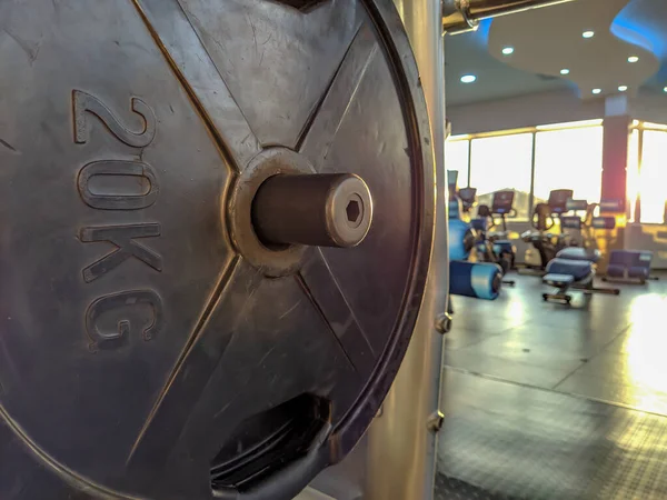 Μαύρο heavy metal χάλυβα των 20 κιλών για την άρση βαρών μέσα σε ένα γυμναστήριο με πολλά διαφορετικά μηχανήματα για την αντοχή και την κατάρτιση — Φωτογραφία Αρχείου