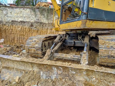 Kazı alanı sarı buldozer yeni bina inşaatı için toprağı ve çamuru kazıyor.