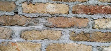 Eski görünümlü taş tuğla kiremitler kahverengi ve turuncu renkli eski bir evin dış cephesinde bulunan çimentoyla yapıştırılmış.