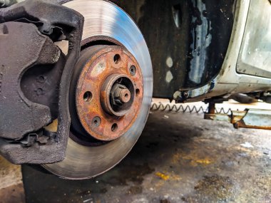 Lastikleri olmayan bir araba, araba tamirhanesinde lastik değiştirirken diske yakın durur.