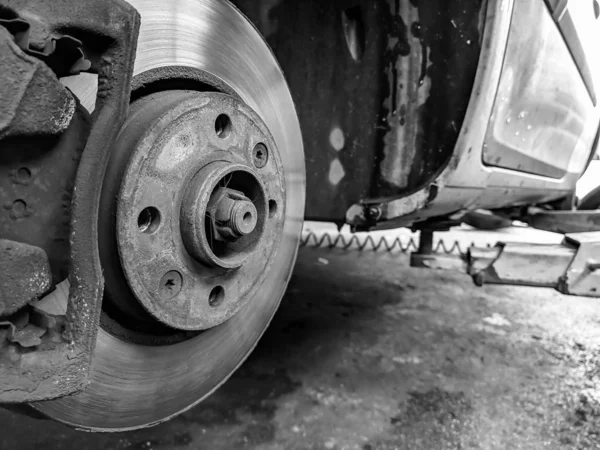 Un coche sin neumáticos en primer plano en blanco y negro listo para tener un nuevo neumático de goma hecho por asistencia mecánica profesional —  Fotos de Stock