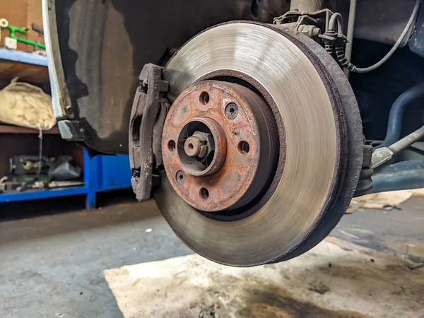 Araba tamirhanesinde lastiği olmayan bir arabanın metal diski daha güvenli sürüş için profesyonel yardımla değiştirilmeye hazır.