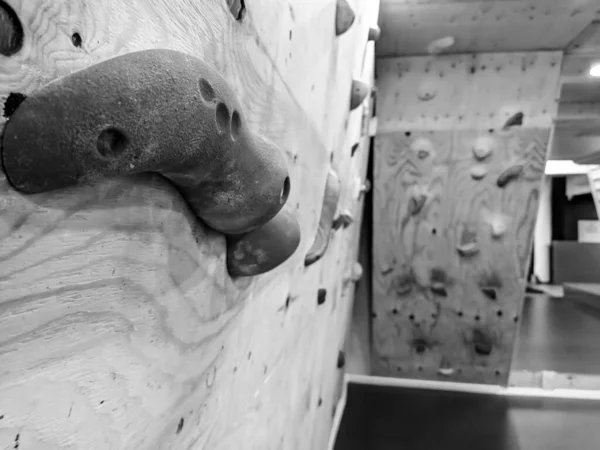 Closeup de parede de escalada ginásio em preto e branco usado para subir e exercício em um esporte extremo e recreativo e para simular um alpinismo penhasco escalada — Fotografia de Stock