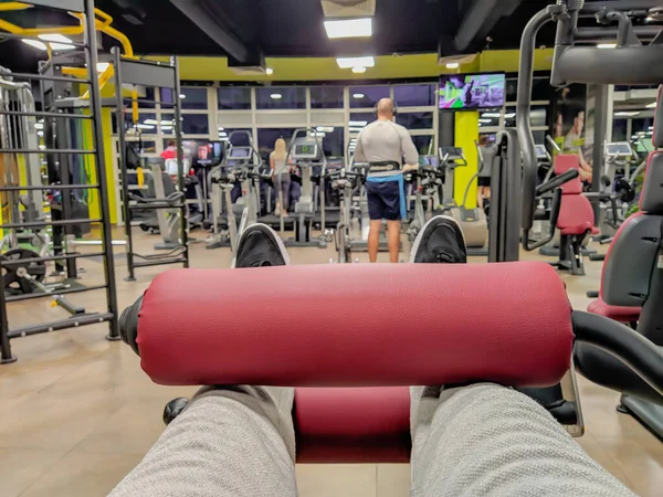 First person view of leg day exercise for heavy weight lifting and body building in a well equipped and modern gym interior with other people working out — Zdjęcie stockowe