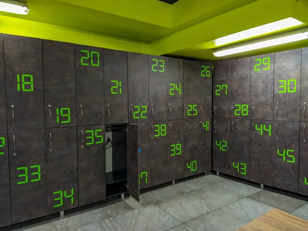Spor salonuna gitmek için yeni yıl kararı. Gri ve yeşil renkli modern bir soyunma odası. Bir dolabı açık.