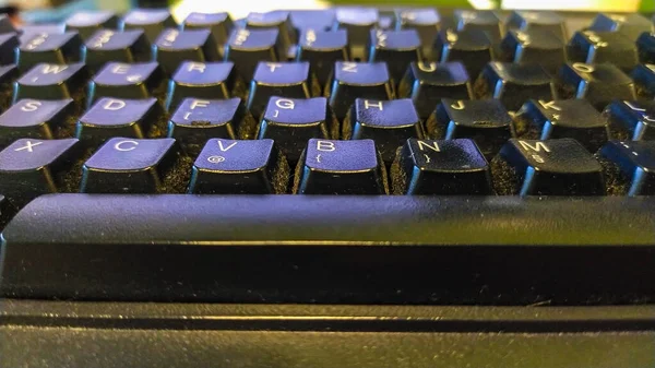 Detailní záběr špinavé černé klávesnice se spoustou prachu uvězněného mezi tlačítky a tlačítky, velmi nehygienické a špinavé podmínky při kancelářské práci — Stock fotografie