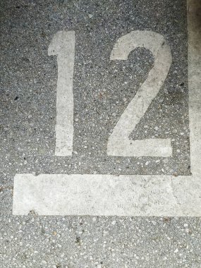 Sokak asfaltında, şehir merkezinde yaprakları ve sokak pislikleri olan bir arabanın park yeri olarak 12 numara yazılıydı.