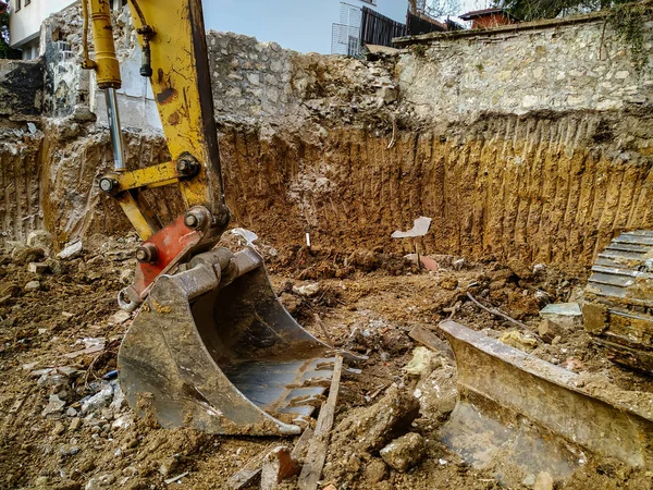 Cabeça de pá bulldozer enorme trabalhando entre a sujeira e lama do local de escavação enquanto cava no local de construção — Fotografia de Stock