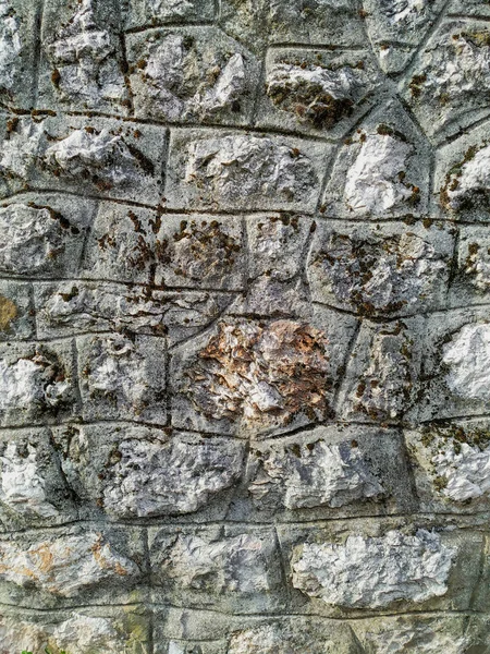 Fond de mur de pierre de roche en briques sur un mur du bâtiment à l'extérieur avec une texture rugueuse et un motif naturel intéressant vieux ciment — Photo