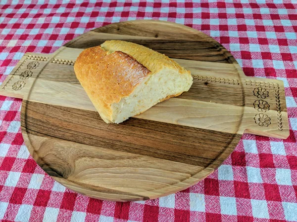Vista superior de um belo pão caseiro na cor dourada que coloca na tábua de corte de madeira e toalha de mesa vermelha colorida, refeição saudável e apetitosa — Fotografia de Stock
