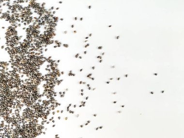 Sağlıklı ve besleyici chia tohumu süper yiyecekler beyaz arkaplandaki görüntünün bir tarafına istiflenmiş ilginç ve rastgele bir çerçeve oluşturuyorlar.