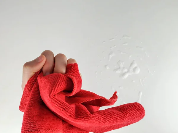 붉은 헝겊을 꽉 쥐고 세척제 거품 이 있는 곳 아래있는 하얀 표면을 닦고 닦을 준비를 하는 여성의 손을 클로즈업 — 스톡 사진
