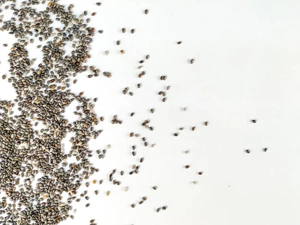 Sağlıklı ve besleyici chia tohumu süper yiyecekler beyaz arkaplandaki görüntünün bir tarafına istiflenmiş ilginç ve rastgele bir çerçeve oluşturuyorlar.