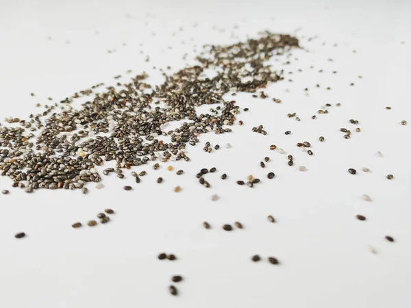 Closeup de sementes de chia em um fundo branco apresentando um alimento nutritivo e saudável cheio de minerais em formato bruto — Fotografia de Stock