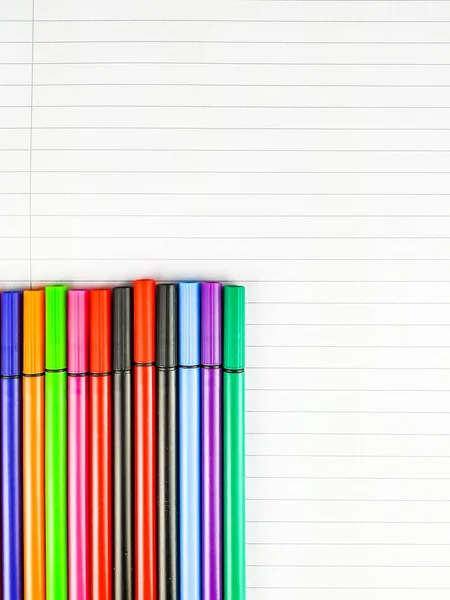 Primer plano de muchos bolígrafos de colores en la esquina izquierda de la imagen colocada en la parte superior del cuaderno blanco y en blanco con líneas para estudiar y tomar notas — Foto de Stock