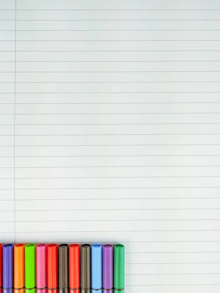 Empty white notebook sheet of paper with lines and colorful pen caps on the lower corner as interesting frame and decoration to empty space to fill — Stock Photo, Image