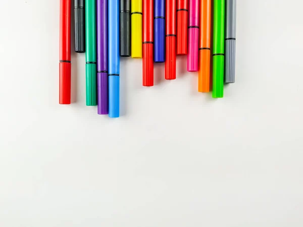 Penne colorate con tappi su sfondo bianco sul lato superiore dell'immagine che creano una cornice interessante per studiare, tornare a scuola, prendere appunti ecc. — Foto Stock