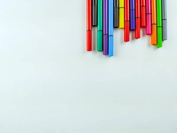 白い背景の上にランダムに並んだカラフルなペンは、学校、大学、着色、空のスペースでメモを取るためのフレームを作ります — ストック写真
