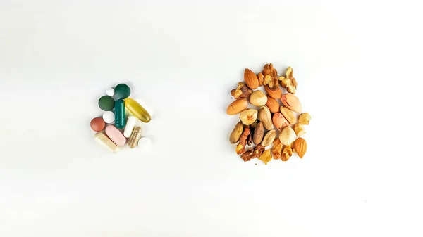 Comparação e conflito entre medicina natural e alternativa com a convencional com nozes e pílulas diferentes em fundo branco — Fotografia de Stock