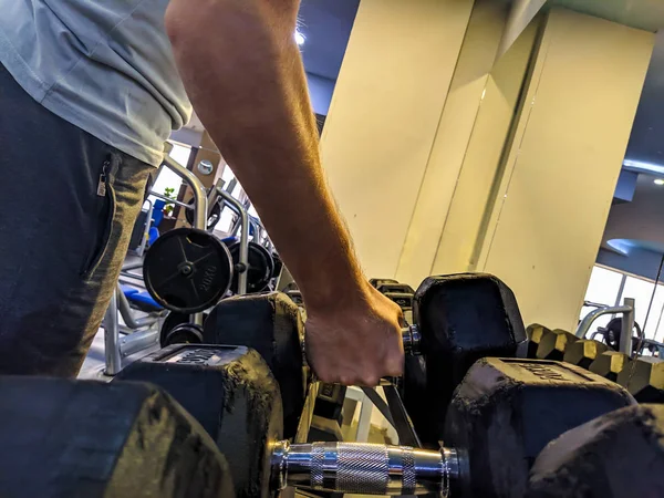 Νεαρός ισχυρός άνδρας χέρι μαζεύοντας ένα βαρίδι μεταλλικό βάρος σε ένα γυμναστήριο για άσκηση, προπόνηση και δύναμη δικέφαλου και απώλεια βάρους — Φωτογραφία Αρχείου