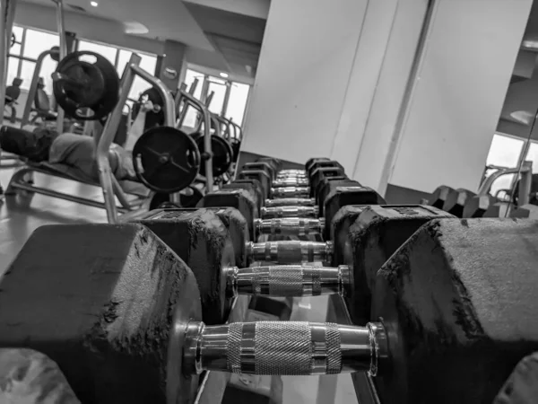 Closeup των επενδεδυμένων αλτήρες σε ένα γυμναστήριο για bodybuilding και αυξάνοντας τη δύναμη και την αντοχή, ενώ άρση του βάρους για πιο ενεργό και υγιή ζωή σε μαύρο και άσπρο — Φωτογραφία Αρχείου