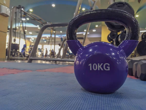 Utrata wagi i zwiększenie siły poprzez wykonywanie ćwiczeń z hantlami kulkowymi o wadze 10 kg na gumowej podłodze sali gimnastycznej w nowoczesnej siłowni — Zdjęcie stockowe
