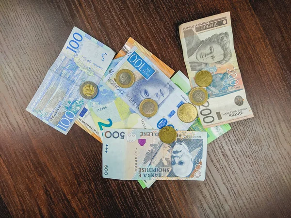 Různé druhy měn v hromadě papírových peněz bankovky a kovové ražené mince na dřevěném pozadí představující zahraniční hojnost a investice — Stock fotografie