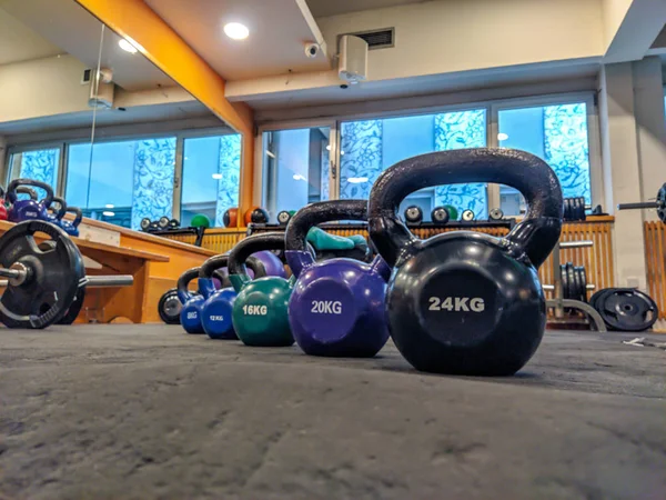 Κουδούνια μπάλα Kettlebell σε στρογγυλό σχήμα σε διάφορα χρώματα και μεγέθη επένδυση στο πάτωμα του γυμναστηρίου έτοιμο να χρησιμοποιηθεί για την απώλεια βάρους και bodybuilding — Φωτογραφία Αρχείου