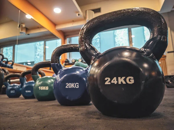Kettlebell dambıllarının farklı renk ve boyutlarda yuvarlak halleri, retro spor salonunun zemininde kilo vermek ve vücut geliştirmek için kullanılmaya hazır.