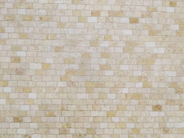 Interesting wall made of beige and other shades of light colors bricks made of stone rocks as an interesting wallpaper background or in home design