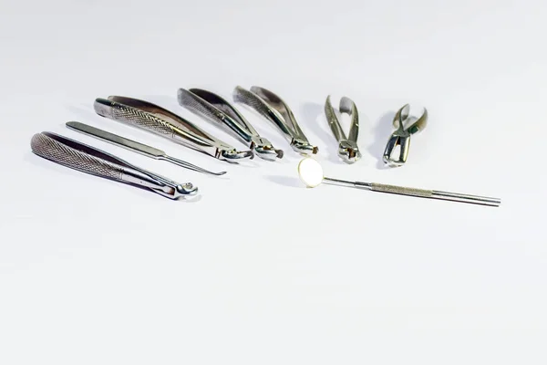 Dentální nástroje, které jsou uspořádány na bílém stole. — Stock fotografie