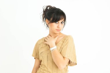 Güzel kız elini boynuna dayayıp, beyaz arka planda, orta ölçekli saçlar topluyor.