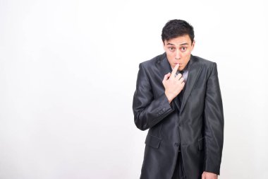 Takım elbiseli sinsi bir adam parmağını ağzına soktu, omuzlarını silkti ve başını eğdi. beyaz arkaplan, orta çekim