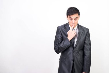 Takım elbiseli sinsi bir adam parmağını ağzına soktu, omuzlarını silkti ve başını eğdi. beyaz arkaplan, orta çekim
