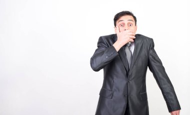 Takım elbiseli adam elleriyle ağzını kapatıyor çünkü istemeden bir şey söyledi. beyaz arkaplan, orta çekim