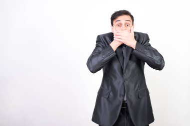 Takım elbiseli adam elleriyle ağzını kapatıyor çünkü istemeden bir şey söyledi. beyaz arkaplan, orta çekim