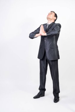 Takım elbiseli adam meditasyon yapıyor, beyaz arka plan, tüm vücut.