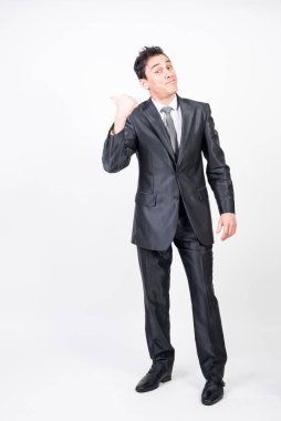 Takım elbiseli gülen adam fotokopi alanını işaret ediyor. Beyaz arkaplan, tüm vücut