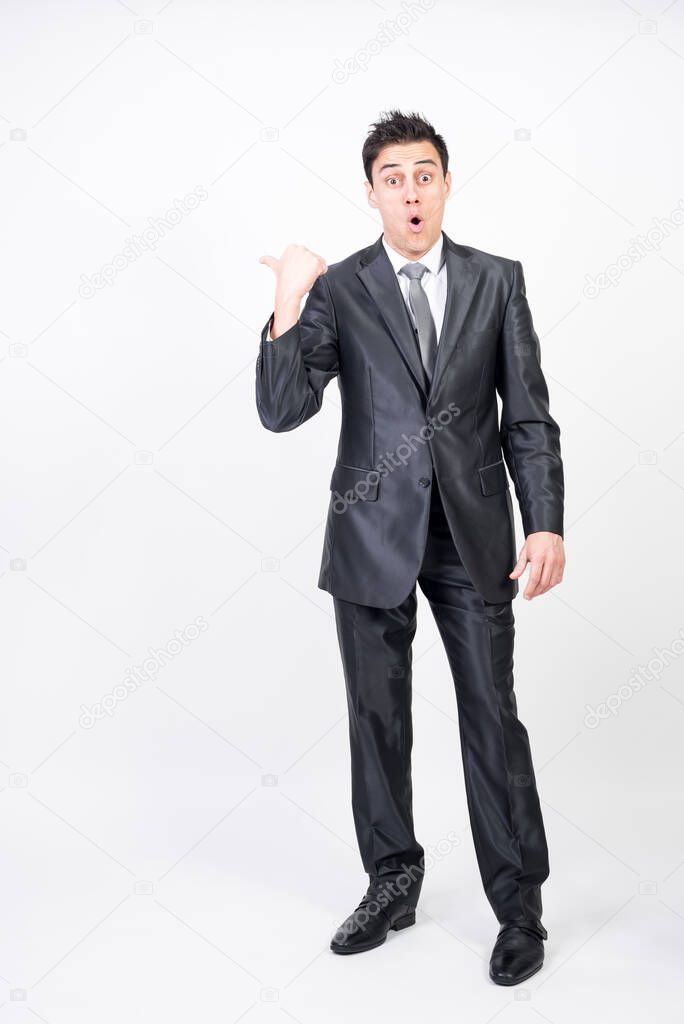 Surprised man in suit pointing to copy space. White background, full body