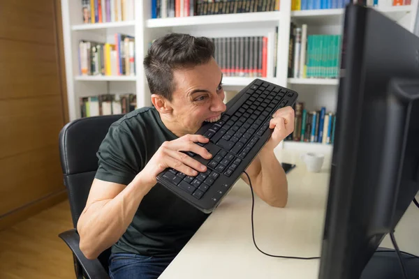 Seated man in a black shirt in front of the computer, hysterical because he does not understand something. Mid shot.
