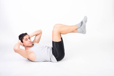 Spor kıyafetli bir adam yerde mekik çekiyor. Beyaz arkaplan, tüm vücut.