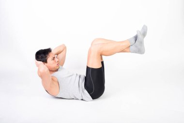 Spor kıyafetli bir adam yerde mekik çekiyor. Beyaz arkaplan, tüm vücut.